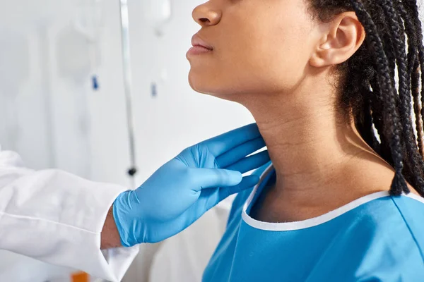 Vista recortada de la mujer afroamericana enferma cuando su médico indio examinando sus ganglios linfáticos - foto de stock