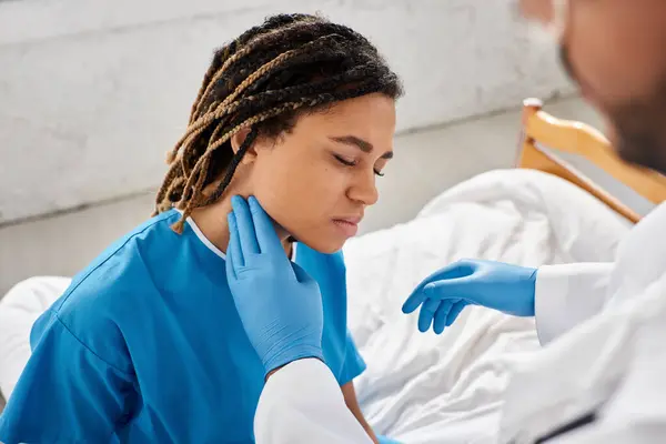 Sick pretty african american woman closing eyes while her indian doctor examining her lymph nodes — Stock Photo