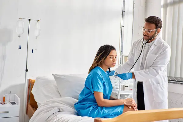 Indian doctor checking breath of his african american female patient in hospital ward, healthcare — Stock Photo
