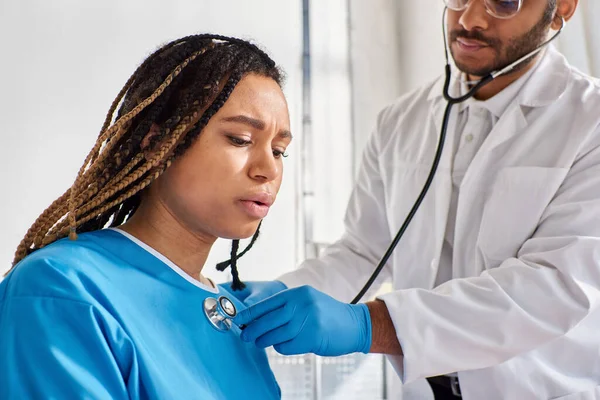 Medico indiano che controlla il respiro della sua paziente afroamericana in ospedale, assistenza sanitaria — Foto stock