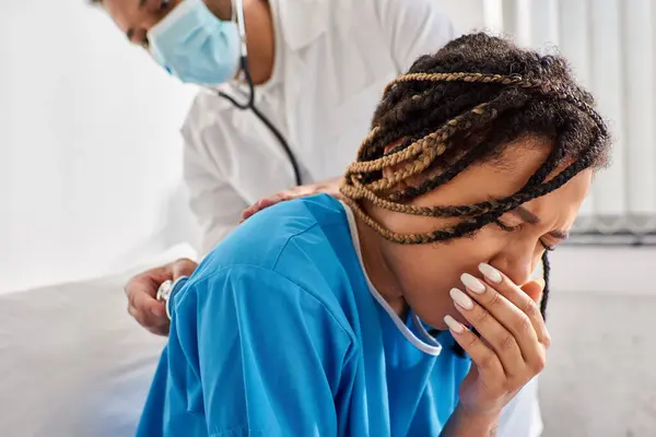 Young indian doctor examining breath of ill african american patient with stethoscope, healthcare — Stock Photo