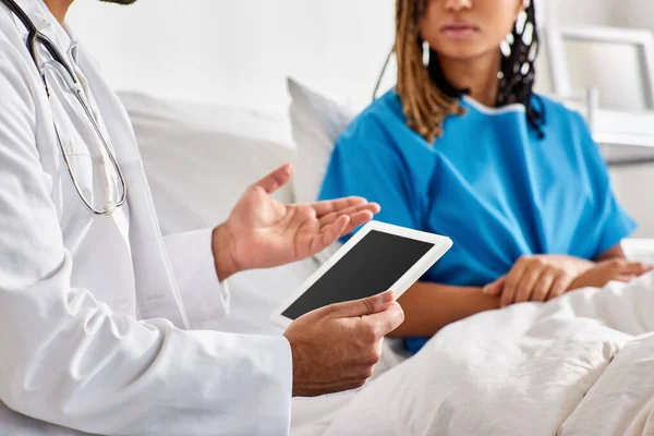 Vista ritagliata di donna afro-americana in letto d'ospedale guardando sfocato medico indiano con tablet — Foto stock