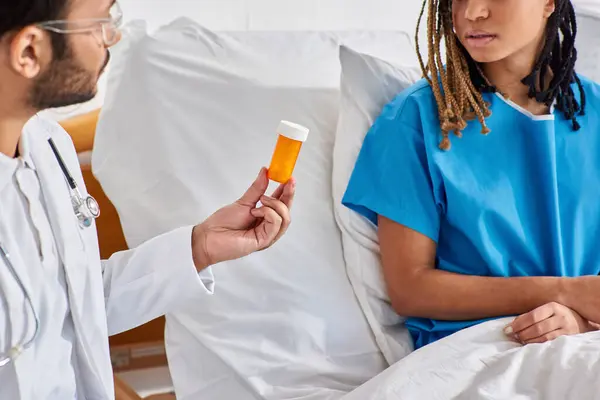 Malata donna afroamericana guardando il suo medico indiano dando le sue pillole mentre nel reparto ospedaliero — Foto stock