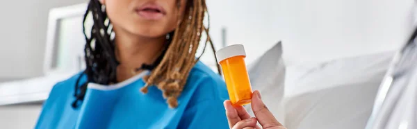 Mujer afroamericana enferma mirando a su médico indio dándole pastillas en el hospital, pancarta - foto de stock