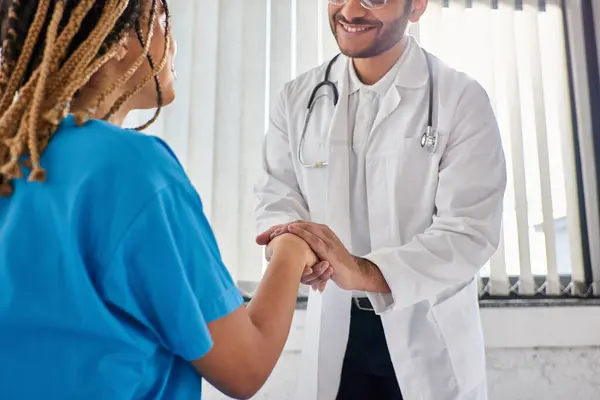 Cropped view of jolly indian doctor shaking hands with his cheerful african american patient — Stock Photo
