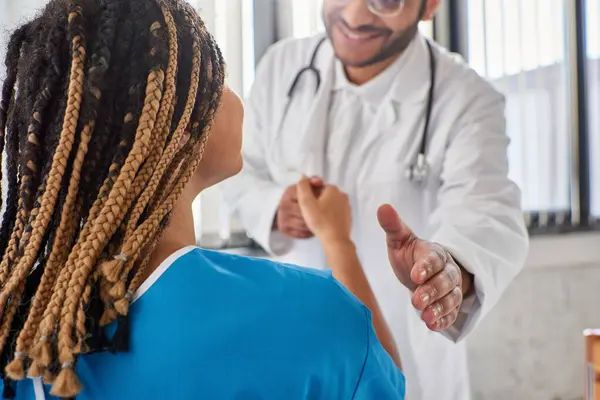 Vista cortada de alegre médico indiano apertando as mãos com seu paciente afro-americano alegre — Fotografia de Stock