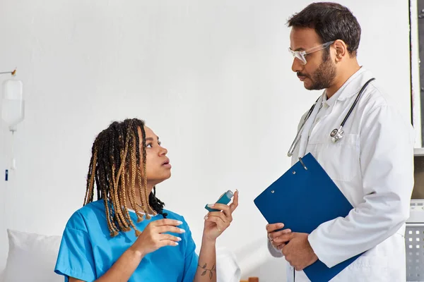 Giovane medico indiano che insegna al suo malato africano americano paziente femminile come usare l'inalatore di asma — Foto stock