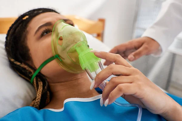 Cropped view of doctor comforting ill african american woman lying in hospital bed with oxygen mask — Stock Photo