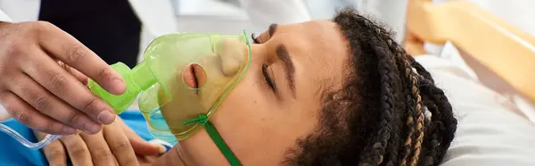 Vista recortada de médico reconfortante mujer afroamericana enferma acostada en la cama con máscara de oxígeno, pancarta - foto de stock