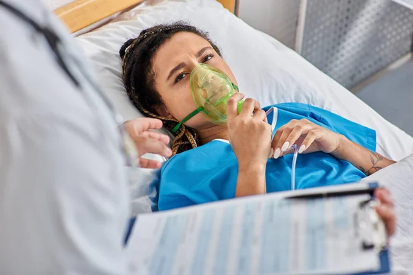 Cropped view of doctor comforting ill african american woman lying in hospital bed with oxygen mask — Stock Photo
