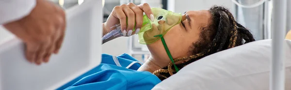 Cropped view of doctor comforting ill african american woman lying in bed with oxygen mask, banner — Stock Photo
