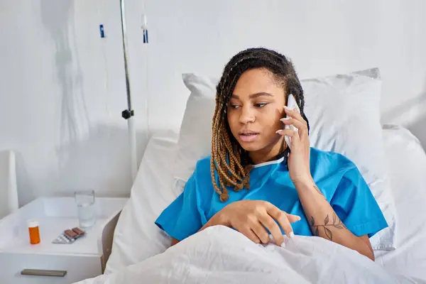 Focada jovem afro-americana conversando por telefone e sorrindo em sua enfermaria hospitalar, saúde — Fotografia de Stock