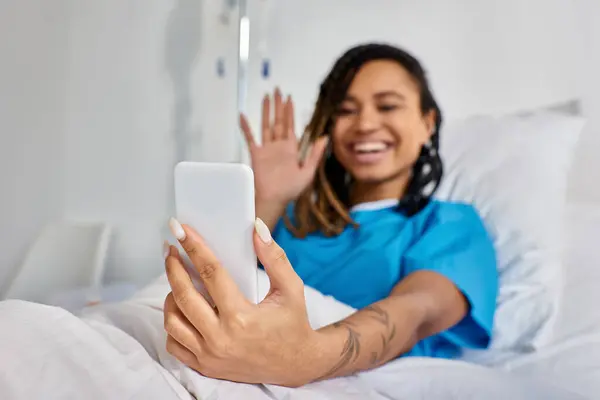Attractive young african american woman having video call while lying in hospital bed, healthcare — Stock Photo
