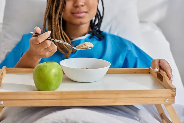 Vista cortada da jovem afro-americana tomando seu café da manhã no leito hospitalar, saúde — Fotografia de Stock