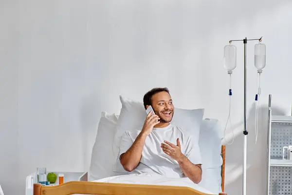 Joyeux jeune homme indien parlant joyeusement par téléphone alors qu'il était couché dans la salle d'hôpital, les soins de santé — Photo de stock