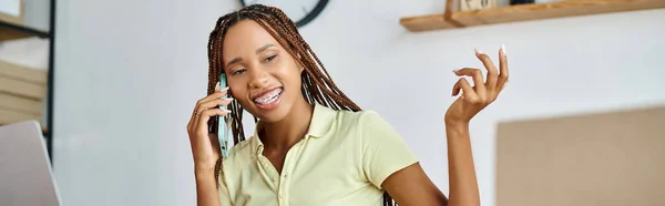 Весёлая африканская американка-ритейлер разговаривает по телефону и улыбается во время упорной работы, баннер — стоковое фото