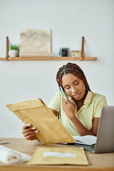 Atraente alegre africano americano vendedor feminino falando por telefone e segurando pacote post, entrega — Fotografia de Stock
