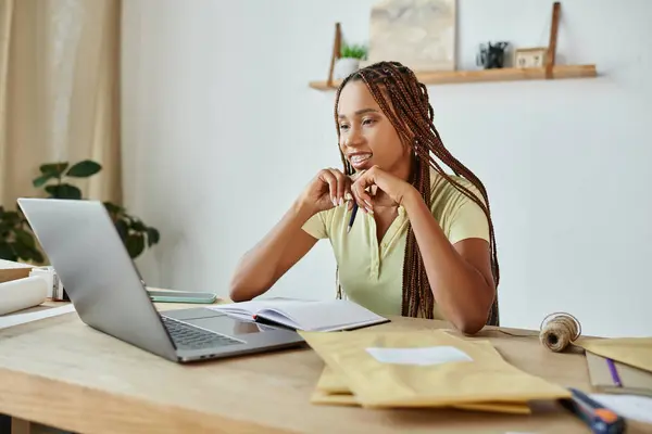 Attraente donna afro-americana venditore guardando felicemente il suo computer portatile mentre si lavora sodo, consegna — Foto stock