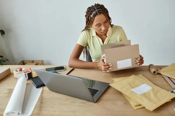 Atractivo joven afroamericano mujer vendedor embalaje caja de cartón cuidadosamente, concepto de entrega - foto de stock