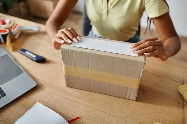 Vista cortada de jovem africano americano vendedor feminino embalagem caixa de papelão, conceito de entrega — Fotografia de Stock