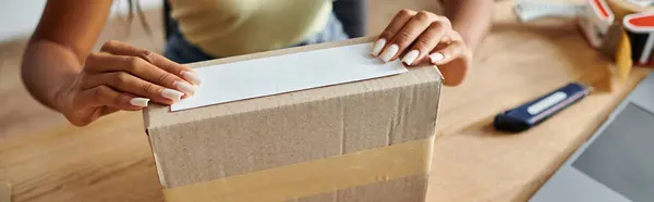 Vista cortada de jovem Africano americano feminino comerciante caixa de embalagem, conceito de entrega, bandeira — Fotografia de Stock