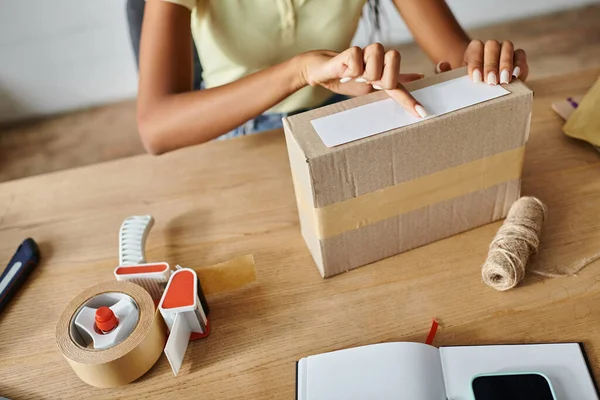 Cropped view of hard working african american female merchant packing box, delivery concept — Stock Photo