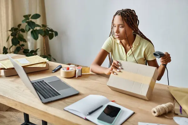 Atractivo joven afroamericano comerciante femenino escaneando código de barras y mirando a la computadora portátil, entrega - foto de stock