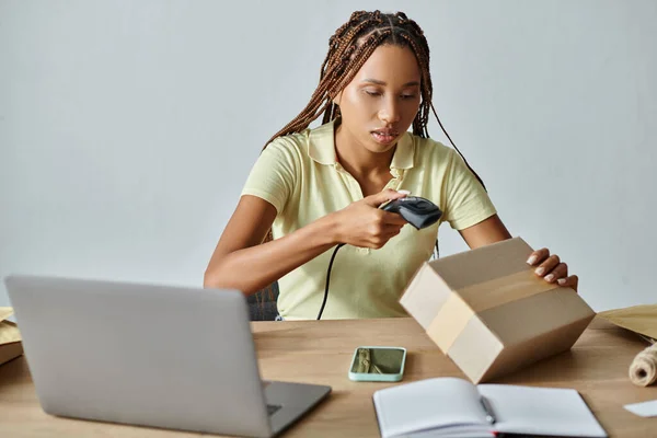 Attractive young african american female retailer scanning cardboard box, delivery concept — Stock Photo