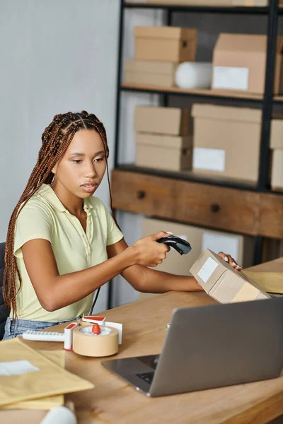 Belle boîte de numérisation vendeur afro-américaine femme et regardant ordinateur portable, concept de livraison — Photo de stock