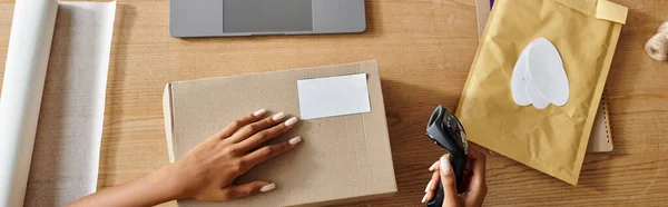 Cropped view of african american woman holding scanner next to box while working hard, delivery — Stock Photo
