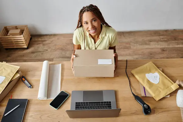 Joyful pretty african american merchant holding box and smiling at camera, delivery concept — Stock Photo