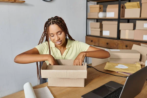 Jubiloso Africano americano comerciante feminino com aparelho caixa de embalagem durante o trabalho, conceito de entrega — Fotografia de Stock