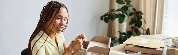 Allegra scatola di imballaggio del venditore afro-americano femminile e guardando laptop, concetto di consegna, banner — Foto stock