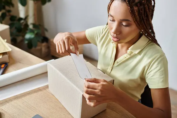 Good looking young african american female merchant putting sticker on box, delivery concept — Stock Photo
