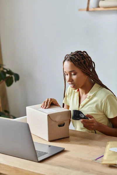Cheerful good looking african american female seller scanning cardboard box during work, delivery — Stock Photo