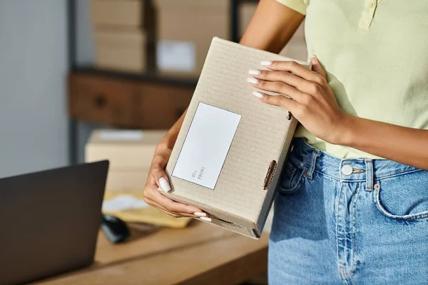 Cropped view of hard working african american female retailer holding box with writing, delivery — Stock Photo