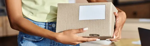 Vista recortada de la caja de espera del vendedor femenino afroamericano joven en el trabajo, concepto de entrega, bandera - foto de stock