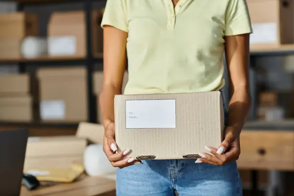 Cropped view of young african american woman holding box with writings during work, delivery — Stock Photo