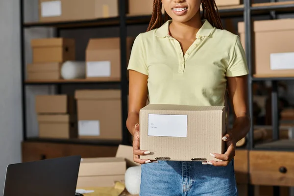 Cropped view of joyous african american female retailer holding box with writings, delivery concept — Stock Photo