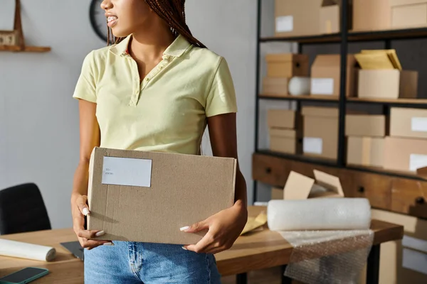 Cropped view of young african american female retailer holding cardboard box, delivery concept — Stock Photo