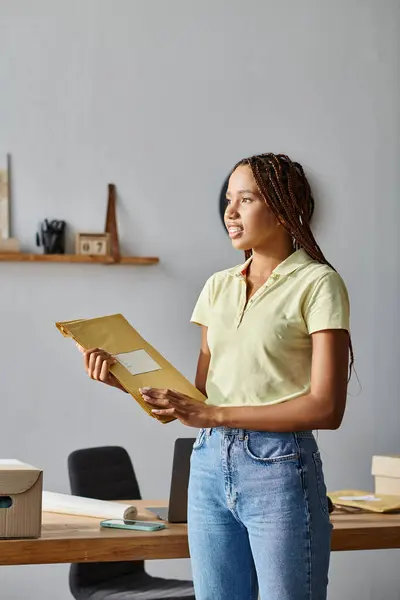 Attractive hard working african american female seller holding post packets and looking away — Stock Photo