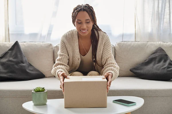 Cheerful good looking african american woman with braces in comfy homewear opening her parcel — Stock Photo