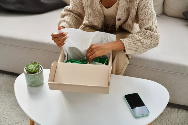 Cropped view of young african american woman unboxing her new green shoes while sitting on sofa — Stock Photo