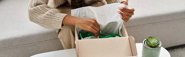 Vista ritagliata di giovane donna afroamericana unboxing il suo pacco con nuove scarpe verdi, banner — Foto stock