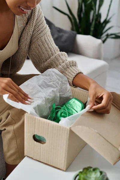 Cropped view of jolly african american woman with braces unpacking her new green shoes at home — Stock Photo