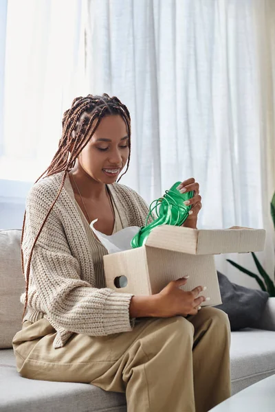 Gut aussehende fröhliche afrikanisch-amerikanische Frau in Homewear beim Auspacken ihrer stylischen neuen grünen Schuhe — Stockfoto