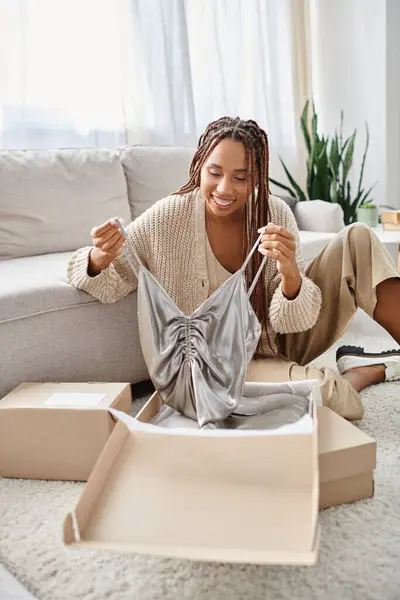 Joyous attractive african american woman unpacking her new chic silver dress and smiling joyfully — Stock Photo