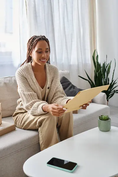 Good looking joyous african american woman in homewear with braces looking at paper post packet — Stock Photo