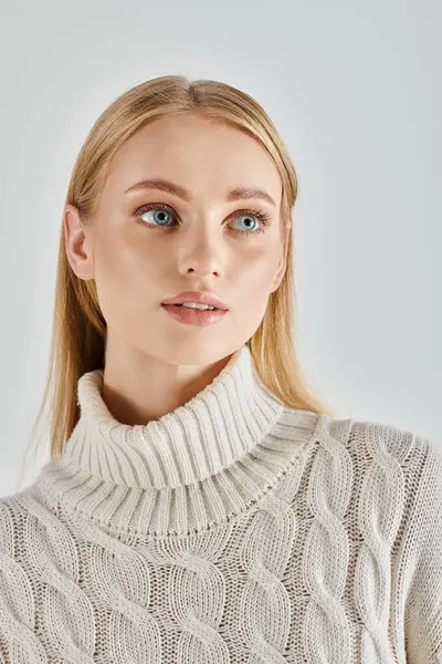 Porträt einer jungen Frau mit natürlichem Make-up, die in weißem Strickpullover auf grauer, zarter Schönheit posiert — Stockfoto