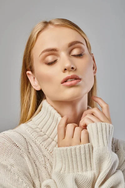 Mulher loira sensual em suéter delicado branco e maquiagem natural com olhos fechados em cinza, retrato — Fotografia de Stock